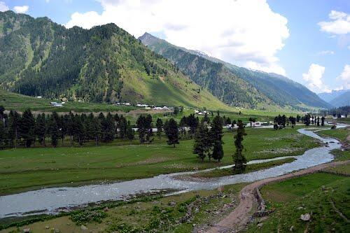 A green river valley with forested mountains in Warwan